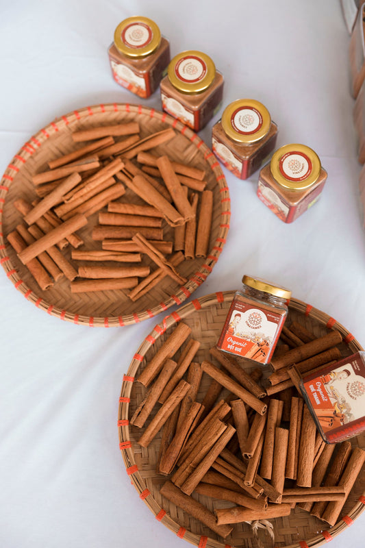 Cinnamon sticks and spice jars arranged on a woven basket, representing natural ingredients that support balanced blood sugar